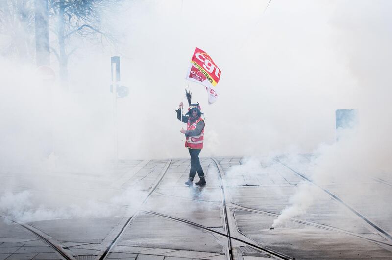 A French CGT unionist holds up the union's flag as he demonstrates against unemployment and precariousness amid smoke bombs in Nantes, western France.  AFP