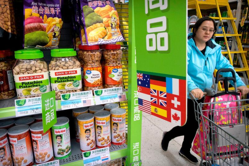 FILE - In this March 23, 2018. file photo, a woman pushes a shopping cart past a display of nuts imported from the United States at a supermarket in Beijing. China raised import duties on a $3 billion list of U.S. pork, fruit and other products Monday, April 2, 2018 in an escalating tariff dispute with President Donald Trump that companies worry might depress global commerce. (AP Photo/Mark Schiefelbein, File)