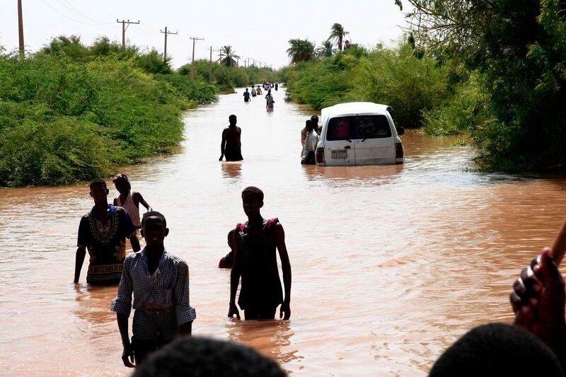 Sudanese people walk a flooded road in Wad Ramli village on the eastern banks of the Nile river. AFP