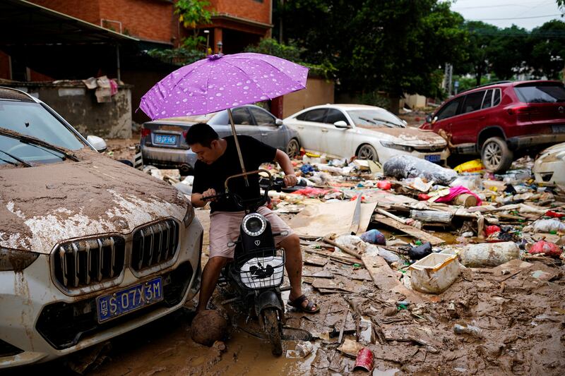 A man rides a scooter through mud and debris after heavy rainfall flooded Tangxia in China's Guangdong province on Saturday. Reuters
