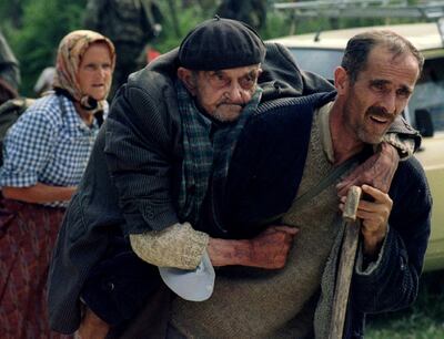 FILE PHOTO: A Bosnian man helps his elderly cousin as they wait to be transported from the eastern Bosnian village of Potocari to Kladanj, near Olovo, July 12, 1995. Bosnia will mark the 25th anniversary of the massacre of more than 8,000 Bosnian Muslim men and boys on July 11, 2020, with many relatives unable to attend due to the novel coronavirus pandemic.  REUTERS/Stringer/File Photo