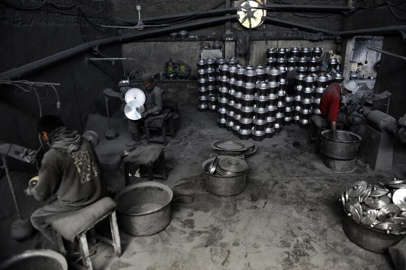Afghan labourers polish metal pots at an aluminium workshop in Herat.
