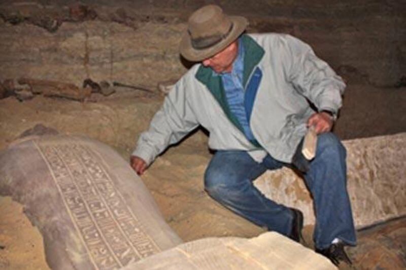 Egypt's top archaeologist Zahi Hawass examines a newly-discovered Egyptian mummy in a sarcophagus in a tomb at Saqqara, south of Cairo.