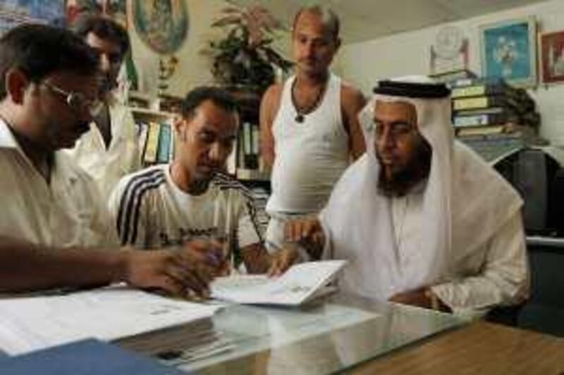 ABU DHABI, UNITED ARAB EMIRATES - July 13, 2009: (right) Ahmed Khamis Al Oraimi, Social Researcher for the Red Crescent sorts through documentation at the Al Otaiba and Garg Contracting LLC labour camp in Mussafah, whose workers have not been paid for the last 8 months.
( Ryan Carter / The National ) *** Local Caption ***  RC004-LabourRedCrescent.JPG