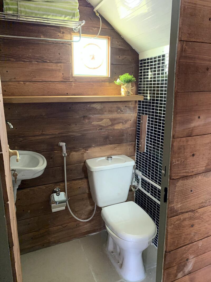 The wood-clad bathroom has a sink and electric shower