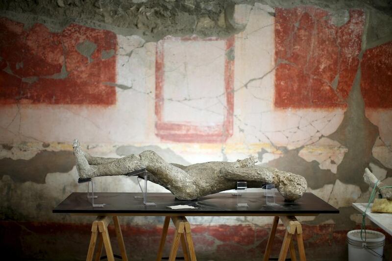 A plaster cast of a Pompeii victim lies in a frescoed room.   Alessandro Bianchi / Reuters