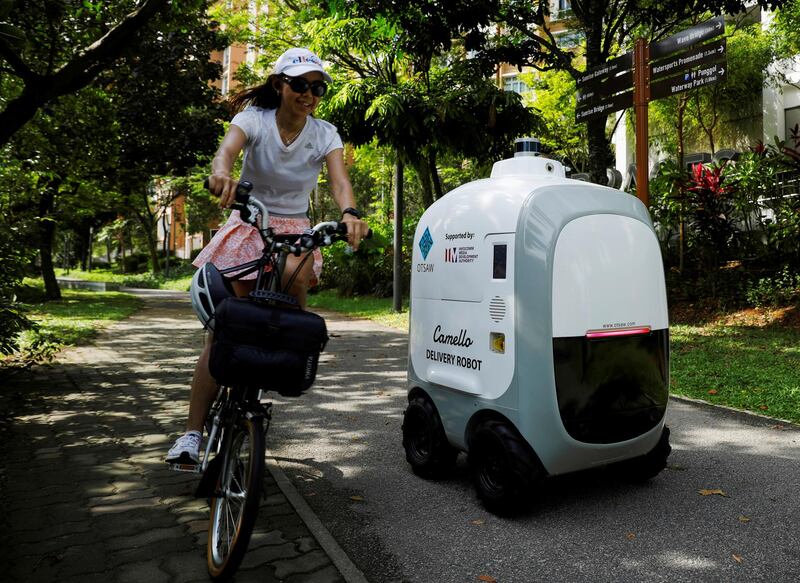 A cyclist passes Camello, an autonomous grocery delivery robot, as it makes a delivery in Singapore. Reuters