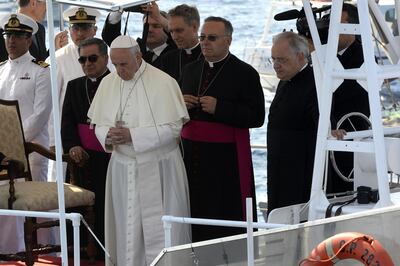 Pope Francis (C) prays after casting a wreath into the sea off Lampedusa island, a key destination of tens of thousands of would-be immigrants from Africa, during his visit on July 8, 2013. In a visit stripped of the usual pomp of papal travel, Francis will cast a wreath into the sea and hold a mass of mourning with a simple cross made from the wood of rickety fishing boats that migrants arrive on.  AFP PHOTO / ANDREAS SOLARO (Photo by ANDREAS SOLARO / AFP)