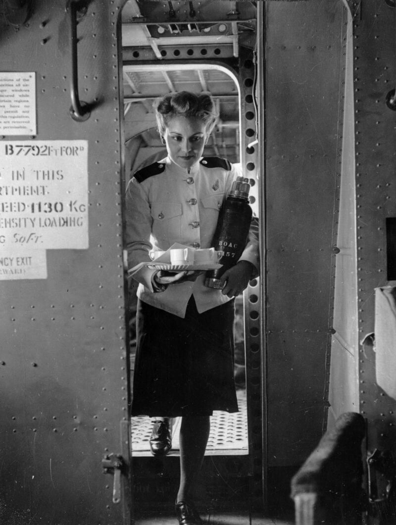 A British Overseas Airways Corporation air stewardess brings a tray of coffee to passengers during a Second World War flight in 1945