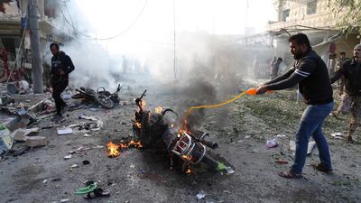 A man tries to put out a fire after a car bomb exploded in Tal Abyad, Syria, Friday, Nov. 2, 2019. A car bomb exploded in a northern Syrian town along the border with Turkey Saturday killing over a dozen of people, Turkey's defense ministry said. (AP Photo)