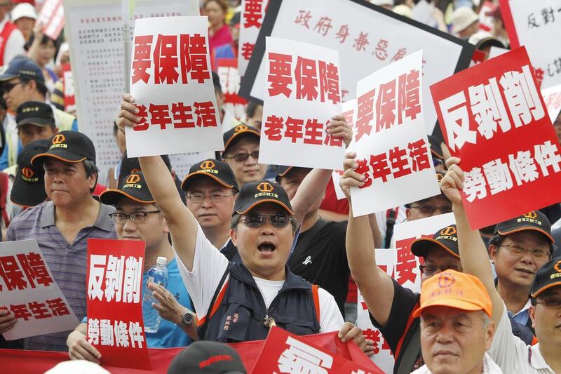 Taiwanese workers hold placards with the words “Against Exploitation” and “Demand Protection for Elderly Lives” during a rally in Taipei. Chiang Ying-ying / AP Photo
