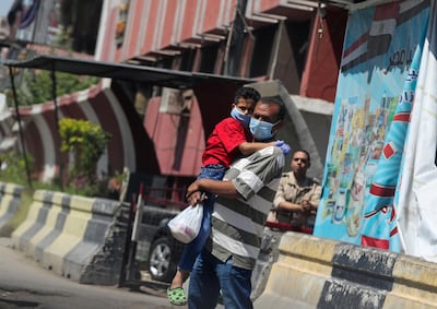 A man wearing a face mask carries his son on the street, as the outbreak of the coronavirus disease (COVID-19) continues, in Cairo, Egypt May 30, 2020. REUTERS/Mohamed Abd El Ghany