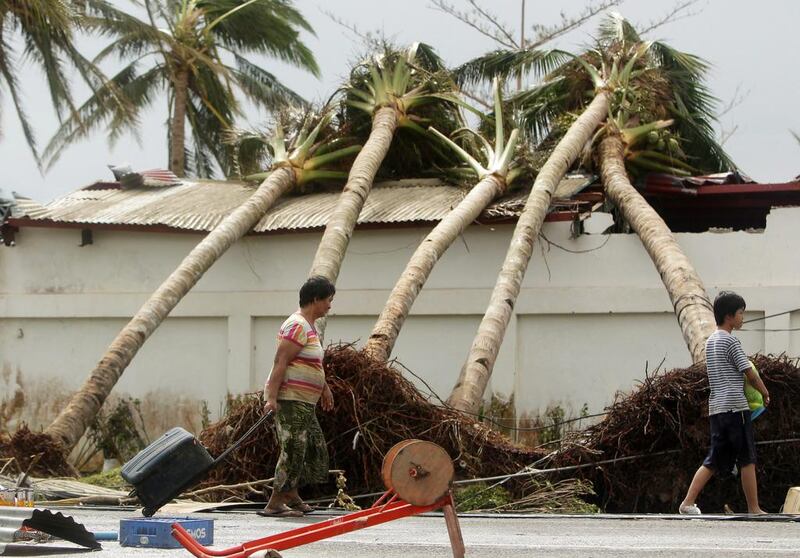 Filipinos walk past uprooted palm trees in Tacloban. Philippine troops began to retrieve bodies strewn in areas devastated by Typhoon Haiyan.

  EPA/FRANCIS R.  MALASIG