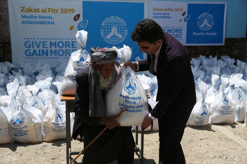 An Afghan elderly man, left, receives free food donated by Muslim Hands, a not-for-profit organization, during the last days of the holy month of Ramadan in Kabul, Afghanistan, Monday, June 3, 2019. Muslims throughout the world are celebrating Ramadan, the holiest month in the Islamic calendar, refraining from eating, drinking, smoking and sex from sunrise to sunset. (AP Photo/Rahmat Gul)