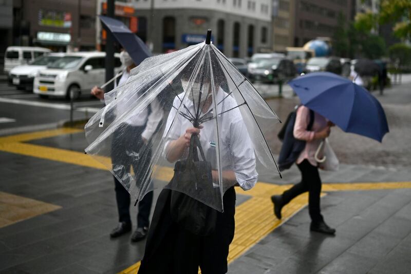 A man tries to shelter under an umbrella as rain and wind from the country's rainy season affects Tokyo. AFP