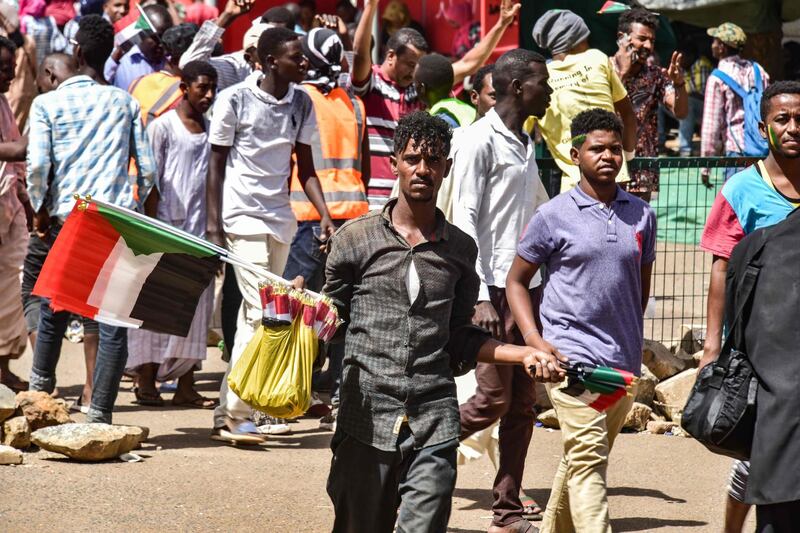 A Sudanese peddlar walks with national flags to be sold during a rally demanding a civilian body to lead the transition to democracy.  AFP