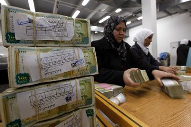 FILE - In this January 13, 2010 file photo, Syrian employees stack packets of Syrian currency in the Central Syrian Bank in, Damascus, Syria. In Syria nowadays, there is an impending fear that all doors are closing. After nearly a decade of war, the country is crumbling under the weight of years-long western sanctions, government corruption and infighting, a pandemic and an economic downslide made worse by the financial crisis in Lebanon, Syria's main link with the outside world. (AP Photo/Hussein Malla, File)