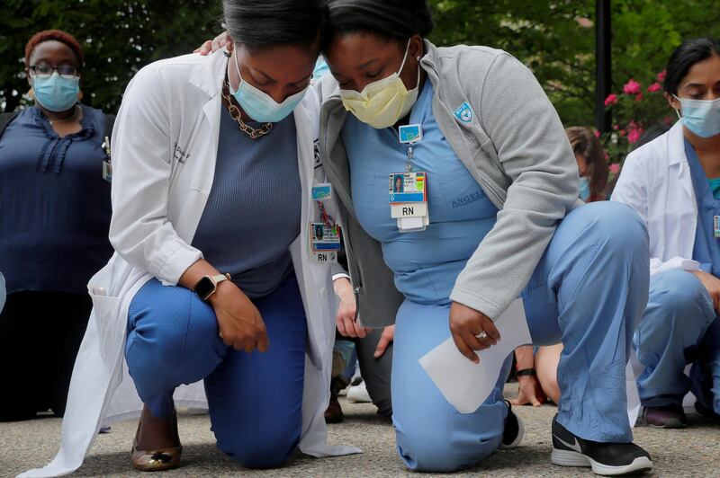 Nurses Sasha Dubois and Farah Fevrin kneel for the eight minutes and 46 seconds of silence during a vigil at Brigham and Women’s Hospital against the death in Minneapolis police custody of George Floyd, in Boston, Massachusetts, on June 5, 2020. Reuters