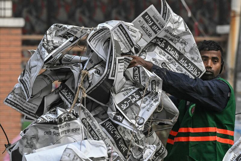 A civic worker dumps election posters a day after the Awami League party led by Prime Minister Sheikh Hasina won Bangladesh's parliamentary elections, in Dhaka. AFP