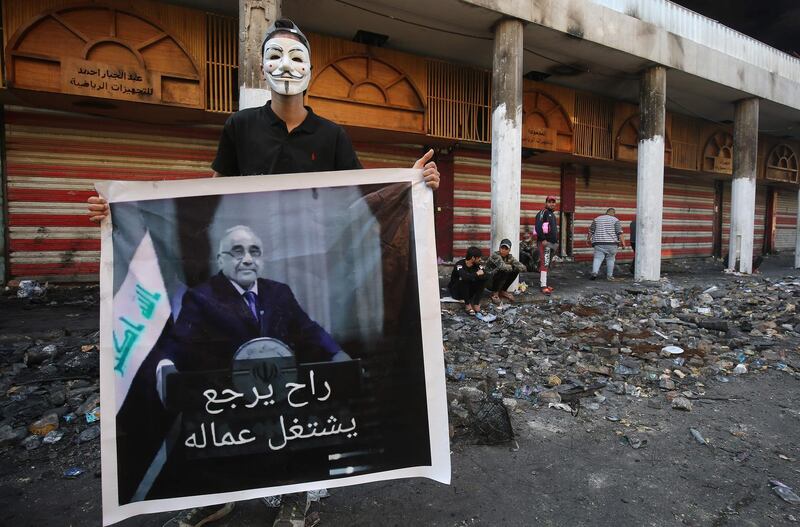 An Iraqi protester holds a picture of the newly resigned prime minister Adel Abdel Mahdi.  AFP