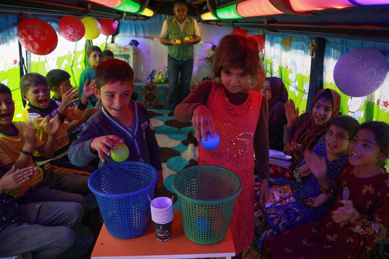 Displaced Syrian children play on a bus converted into a classroom.