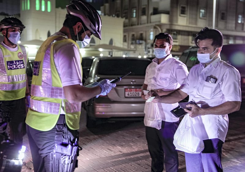 Abu Dhabi, United Arab Emirates, May 11, 2020.   Abu Dhabi Police bicycle patrol do night operations around the Mussaffah area to warn or catch curfew violators in the residential areas.  --  Police officers check on Emirates Identification on curfew violators.
Victor Besa / The National
Section:  NA
Reporter:  Haneen Dajani