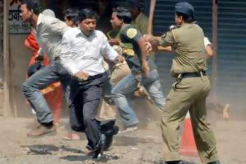 A police officer baton charges hard-line Maharashtra Reconstruction Party supporters in Mumbai, India, Tuesday, Oct. 21, 2008. The firebrand leader of the party Raj Thackeray facing charges of inciting violence against migrant workers in India's financial capital was granted bail in one district Tuesday but continued to remain under arrest for violence in another area. On Sunday dozens of Thackeray’s supporters attacked students from northern India who had traveled to Mumbai on the west coast of India to apply for jobs on the railways. (AP Photo/Rajanish Kakade)