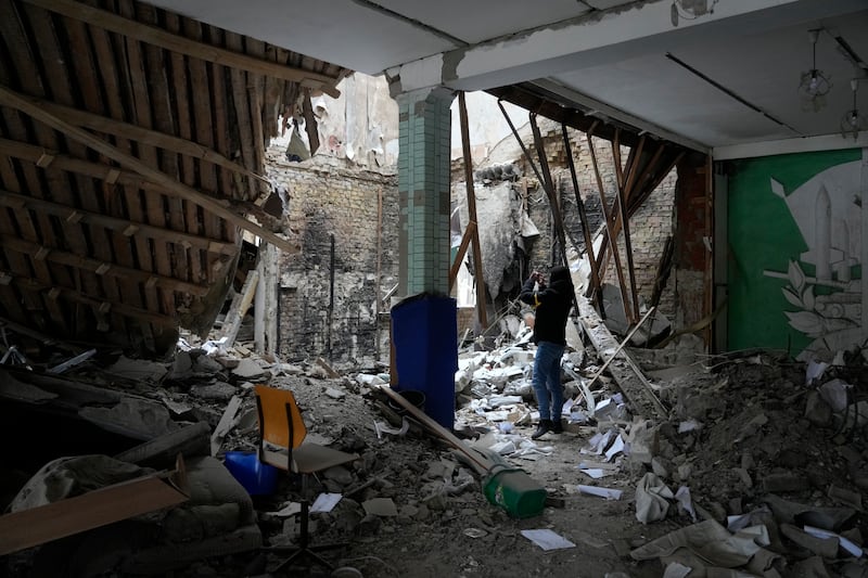 A woman takes photos of a destroyed accommodation building near a checkpoint in Brovary, outside Kiev. AP