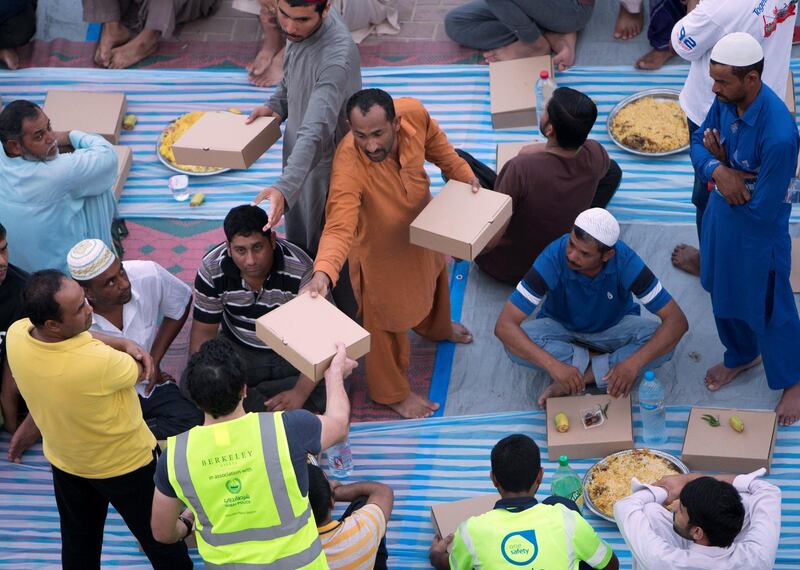 DUBAI, UNITED ARAB EMIRATES -  Volunteers with iftar meal boxes distributing them to the workers.  Dubai Police join hands with Berkeley Assets to serve up Iftar dinner to mark Laylatul Qadr for 10,000 labourers with seating for 5,000 and another 5,000 laborers will go home with meal boxes in Al Muhaisnah, Dubai.  Ruel Pableo for The National
