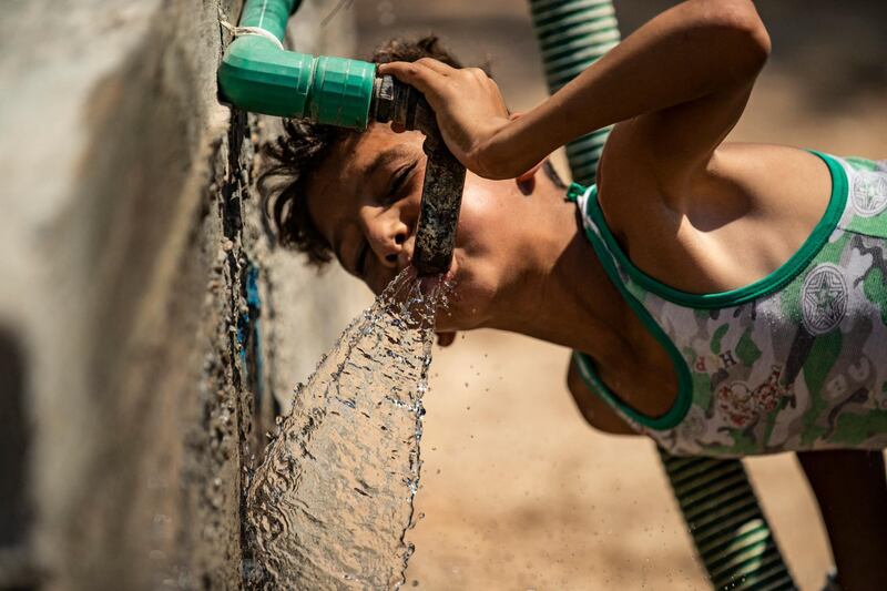 A Syrian boy drinks from the faucet of a water cistern provided by humanitarian organisations during a water outage in Syria's northeastern city of Hasakah on August 22, 2020. - As coronavirus spreads across northeast Syria, residents in Hasakeh have been caught up in the latest spat between Turkish forces to the north and Syrian Kurds it views as "terrorists". In October last year, Turkish forces occupied a 120-stretch (70-mile) stretch of land inside the Syrian border, including the Alouk power station that supplies drinking water to Hasakeh. Kurdish officials and analysts say now Turkey is using the water station to pressure the Kurdish authorities into giving them more electricity in the region they took from them. (Photo by Delil SOULEIMAN / AFP)