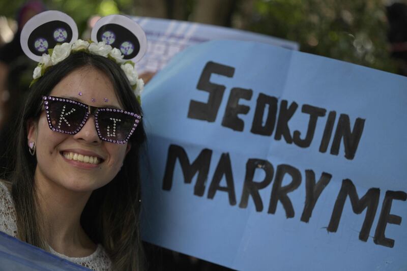 A fan has a sign asking Jin to marry her. 