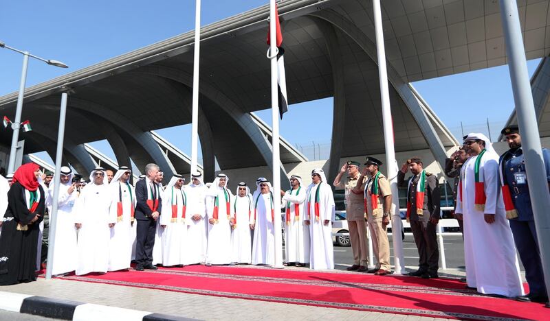 Sheikh Ahmed bin Saeed Al Maktoum (C), chairman and chief executive of Emirates Airline and Group, raises the UAE flag in front of Dubai International Airport. EPA