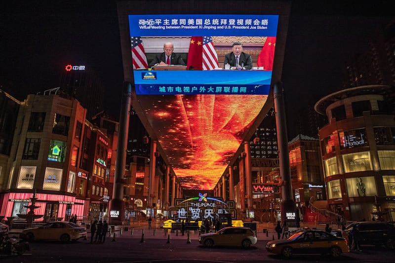 People walk past a big screen showing Mr Biden, left, and Chinese President Xi Jinping attending a virtual summit on November 16. EPA