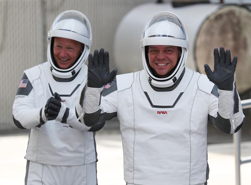 (FILES) In this file photo taken on May 30, 2020, NASA astronauts Bob Behnken (R) and Doug Hurley walk out of the Operations and Checkout Building on their way to the SpaceX Falcon 9 rocket with the Crew Dragon spacecraft on launch pad 39A at the Kennedy Space Center in Cape Canaveral, Florida.  The first US astronauts to reach the International Space Station on an American spacecraft in nearly a decade might not come home this weekend as scheduled because of Hurricane Isaias, NASA said July 31, 2020. / AFP / GETTY IMAGES NORTH AMERICA / JOE RAEDLE
