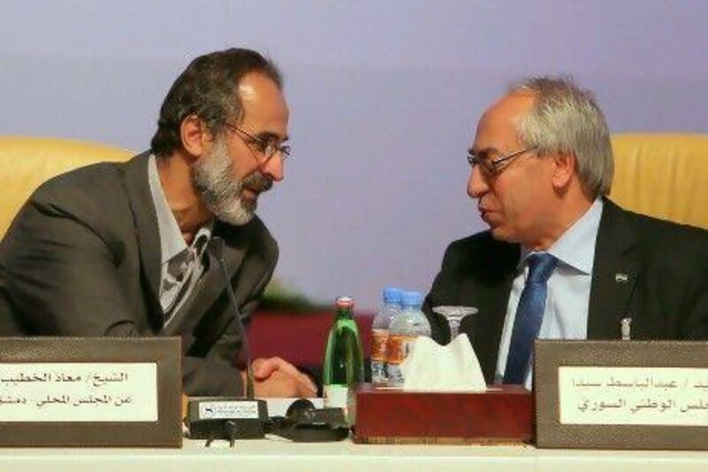 Ahmed Moaz Al Khatib, left, a moderate who quit Syria three months ago, chats with outgoing National Syrian Council chief Abdulbaset Saida during the meeting to form Syria’s new opposition.