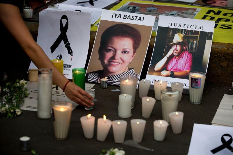 FILE - In this May 16, 2017, file photo, a woman places a candle in front of pictures of murdered journalists Miroslava Breach, left, and Javier Valdez during a demonstration against the killing of journalists, outside the Interior Ministry in Mexico City. Mexican authorities have arrested a man suspected of ordering the March killing of journalist Breach. The National Security Commission said in a statement that the suspect was detained along with two others Monday, Dec. 25, in the town of Bacobampo, Sonora state. (AP Photo/Rebecca Blackwell, File)