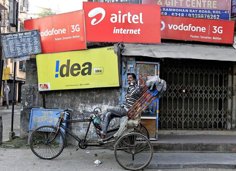 A rickshaw puller speaks on his mobile phone as he waits for customers in front of advertisement billboards belonging to telecom companies in Kolkata. Reuters