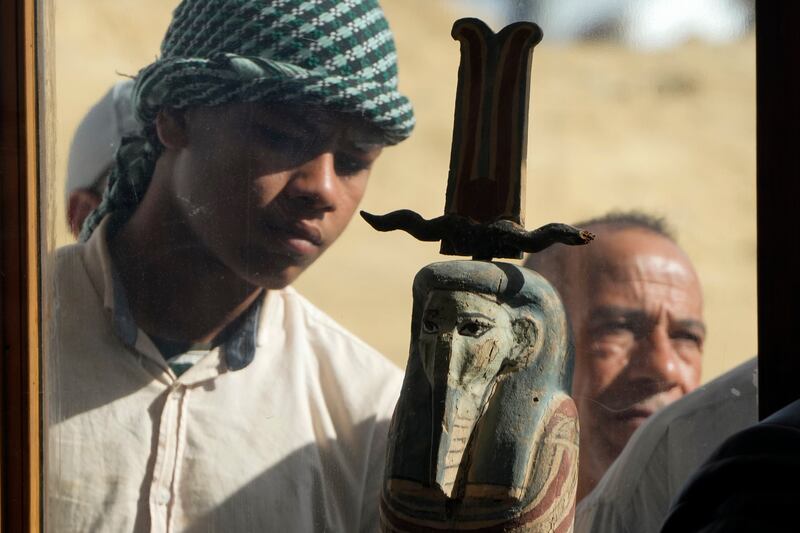 An Egyptian antiquities worker studies a recently discovered artefact at Saqqara. AP Photo