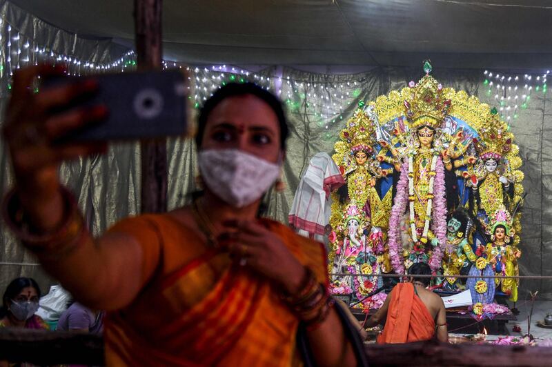 A Hindu devotee takes a selfie as priests perform traditional prayers in front of the idol of ten-handed Hindu Goddess Durga during the 'Durga Puja' festival in Chennai, India. AFP