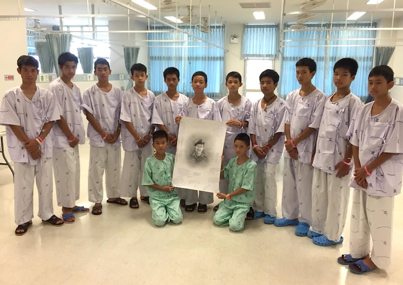 The 13 rescued football team members, holding a portrait of former Thai Navy Seal, Petty Officer 1st class Saman Kunan, who died during rescue efforts in Tham Luang cave, as they pose in Chiang Rai province, Thailand. EPA