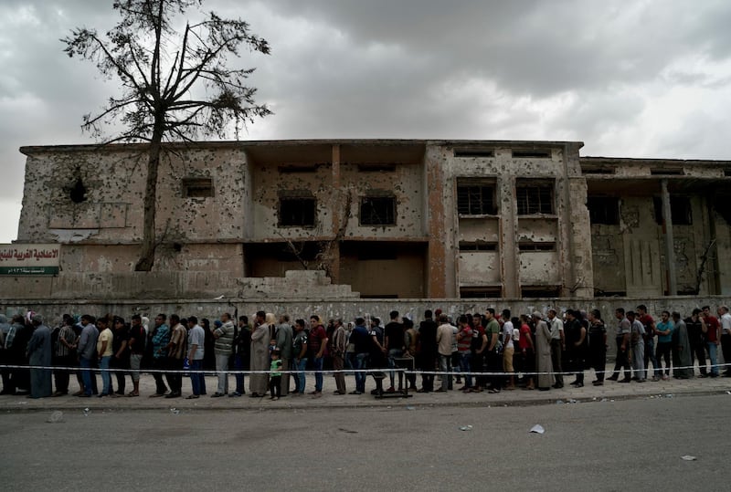 Iraqis wait in a long line to cast their vote in the country's parliamentary elections at a polling site in a battle-damaged building in west Mosul, Iraq, Saturday, May 12, 2018. This is the first parliamentary election since the Islamic State group was driven from the city.(AP Photo/Maya Alleruzzo)
