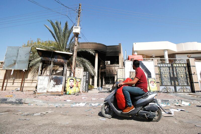 A man rides his motorcycle past the burnt-out headquarters MP Faleh Al Khazali. Reuters
