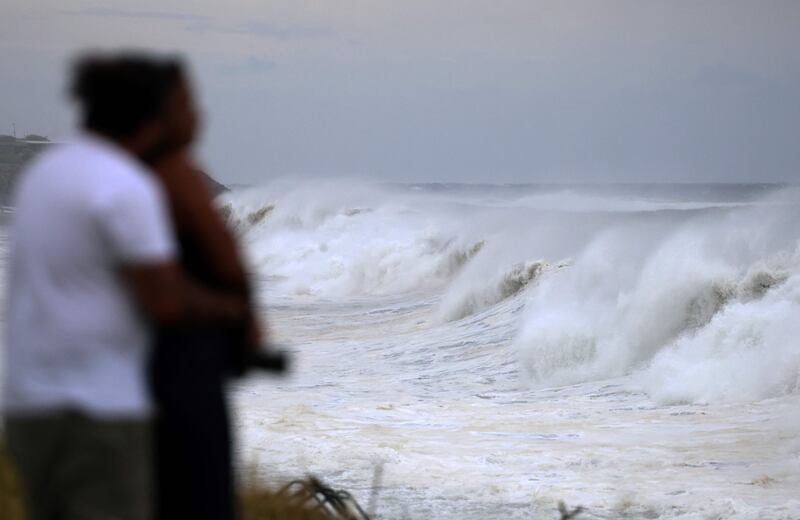 People watch waves as they crash along the shore as Cyclone Freddy nears the island of La Reunion. AFP