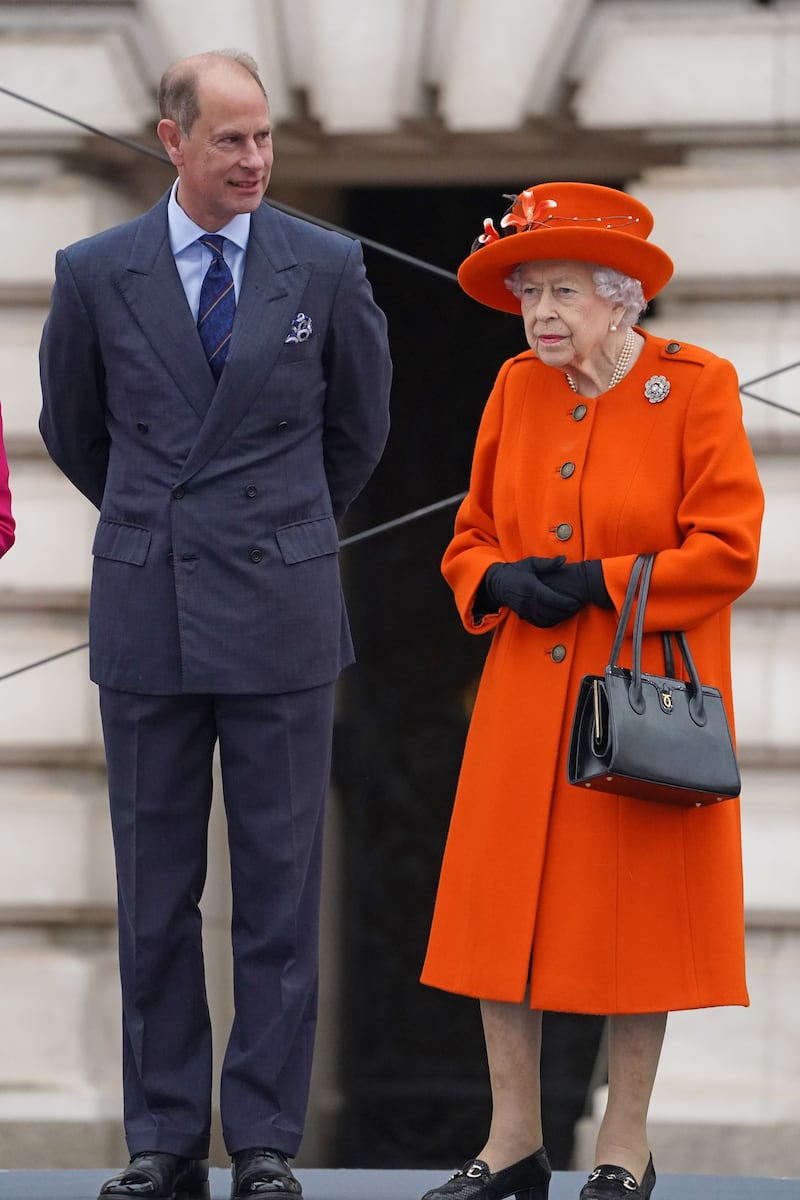 Queen Elizabeth II, wearing orange, and Prince Edward, Earl of Wessex, at Buckingham Palace on October 7, 2021, for the launch of the queen's Baton Relay for Birmingham for the 2022 Commonwealth Games. Getty Images