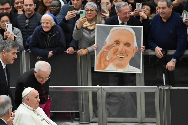 A visitor holds a portrait of Pope Francis as he passes by the crowd before his weekly general audience in the Paul VI hall at the Vatican on January 11, 2023.  (Photo by Alberto PIZZOLI  /  AFP)