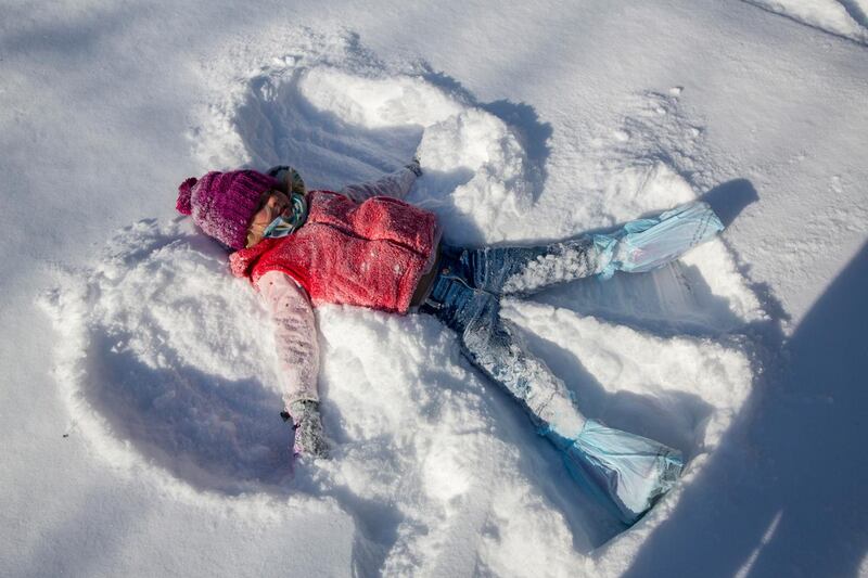Annie Boon, 5, creates a snow angel while sledging with her family in Austin. AP