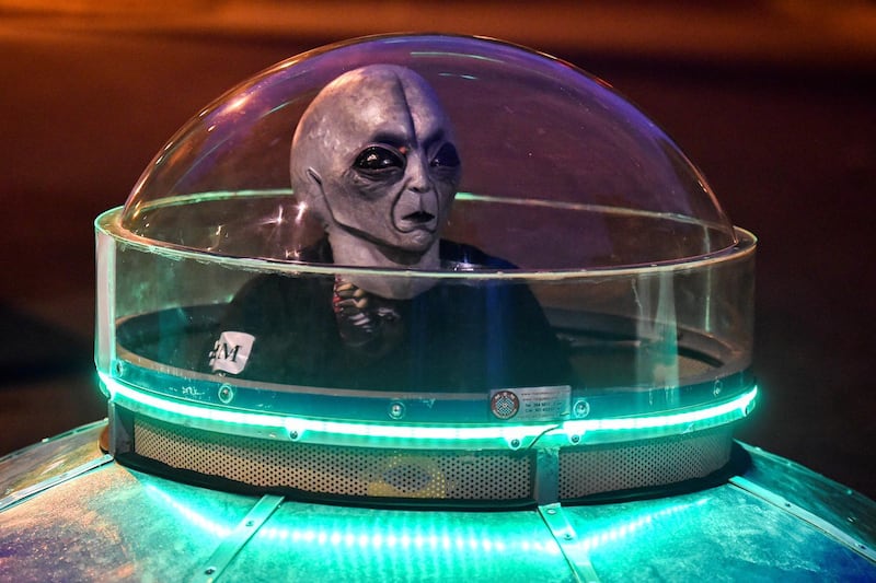 A masked man rides a UFO-shaped toy car at a park in Cali, Colombia before a night curfew starts against the spread of the new coronavirus. AFP