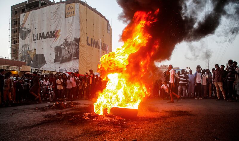 Sudanese protesters chant slogans next to burning tyres.  EPA