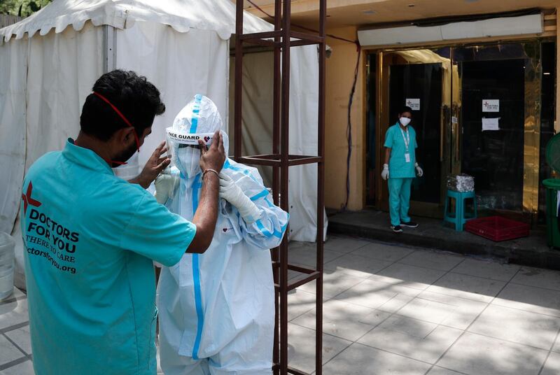 A health worker adjusts the face shield of another as she prepares to go inside a quarantine centre for Covid-19 patients in New Delhi. India now has reported more than 15 million coronavirus infections, a total second only to the US. AP