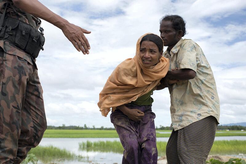 An injuried Rohingya woman is stoped from a Bengali ¿? to get aid out of the restricted area of the newbrand refugee camp shettled on a no man land between Bangladesh and Myanmar 